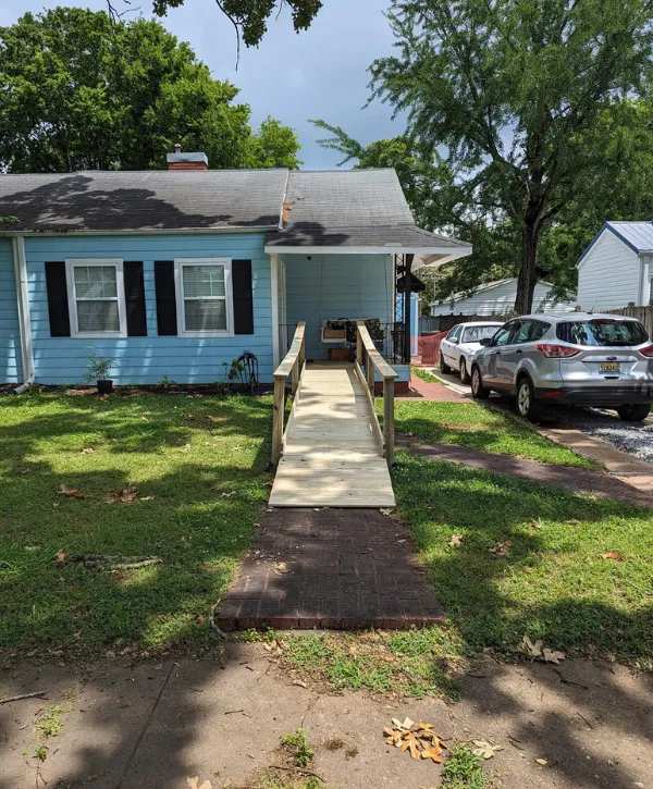 Wide wooden entry ramp with railings installed for home accessibility