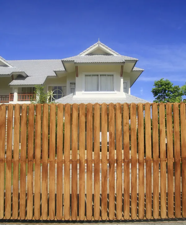 Tall wooden privacy fence in front of a suburban house with a gabled roof
