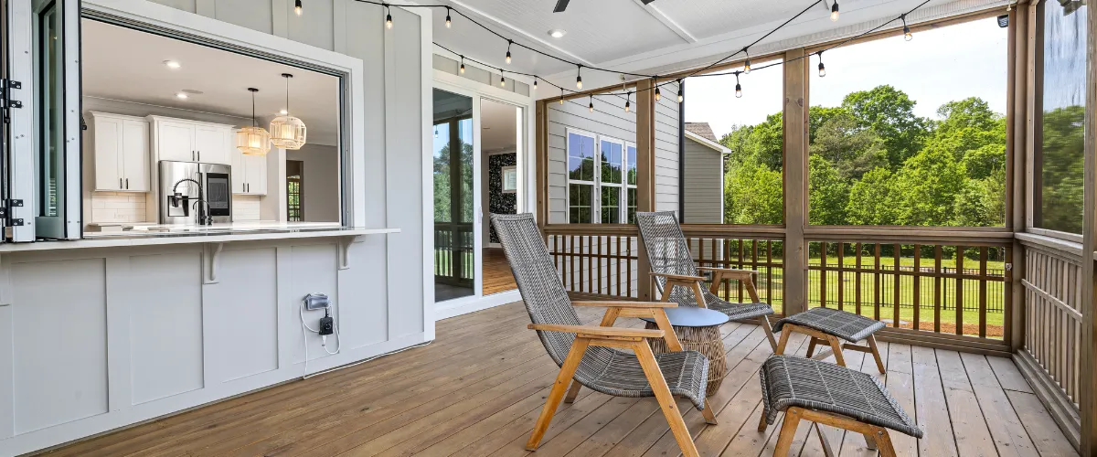 Screened porch with comfortable seating, wooden deck, and open kitchen window pass-through