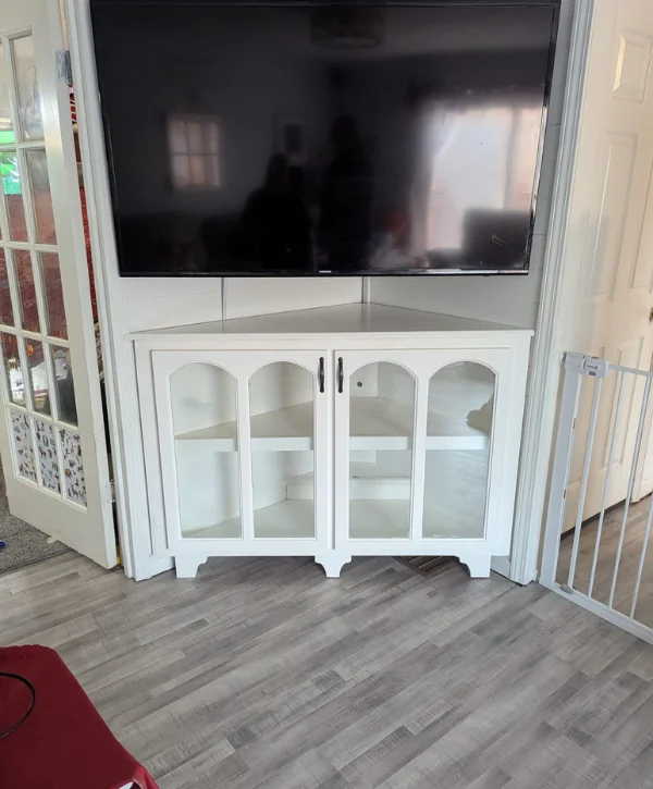 Custom corner TV cabinet with storage shelves and mounted television.
