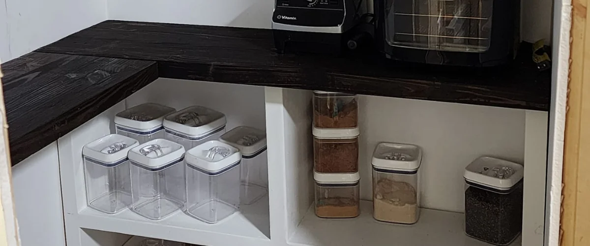 Custom pantry shelving with organized food storage containers and countertop appliances.