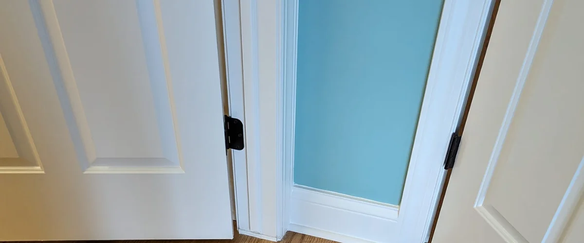 A close-up view of the bottom portion of a white French door, revealing a frosted blue glass panel.