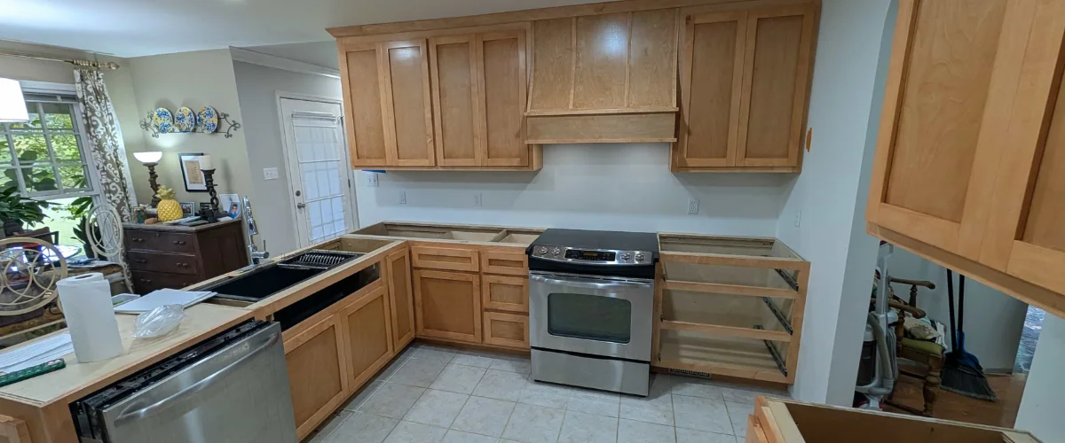 A kitchen under renovation with light wood upper cabinets installed, a stainless steel range, and base cabinets awaiting countertops. A kitchen under renovation with light wood upper cabinets installed, a stainless steel range, and base cabinets awaiting countertops.