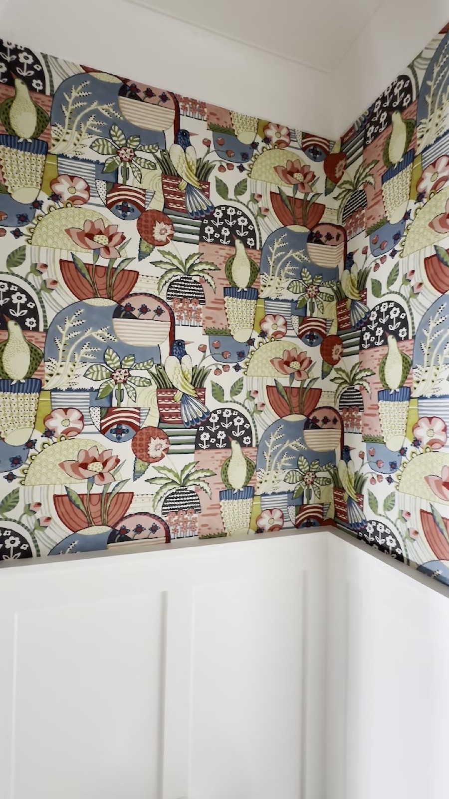 Patterned mural wallpaper above wainscoting, matched across the corner