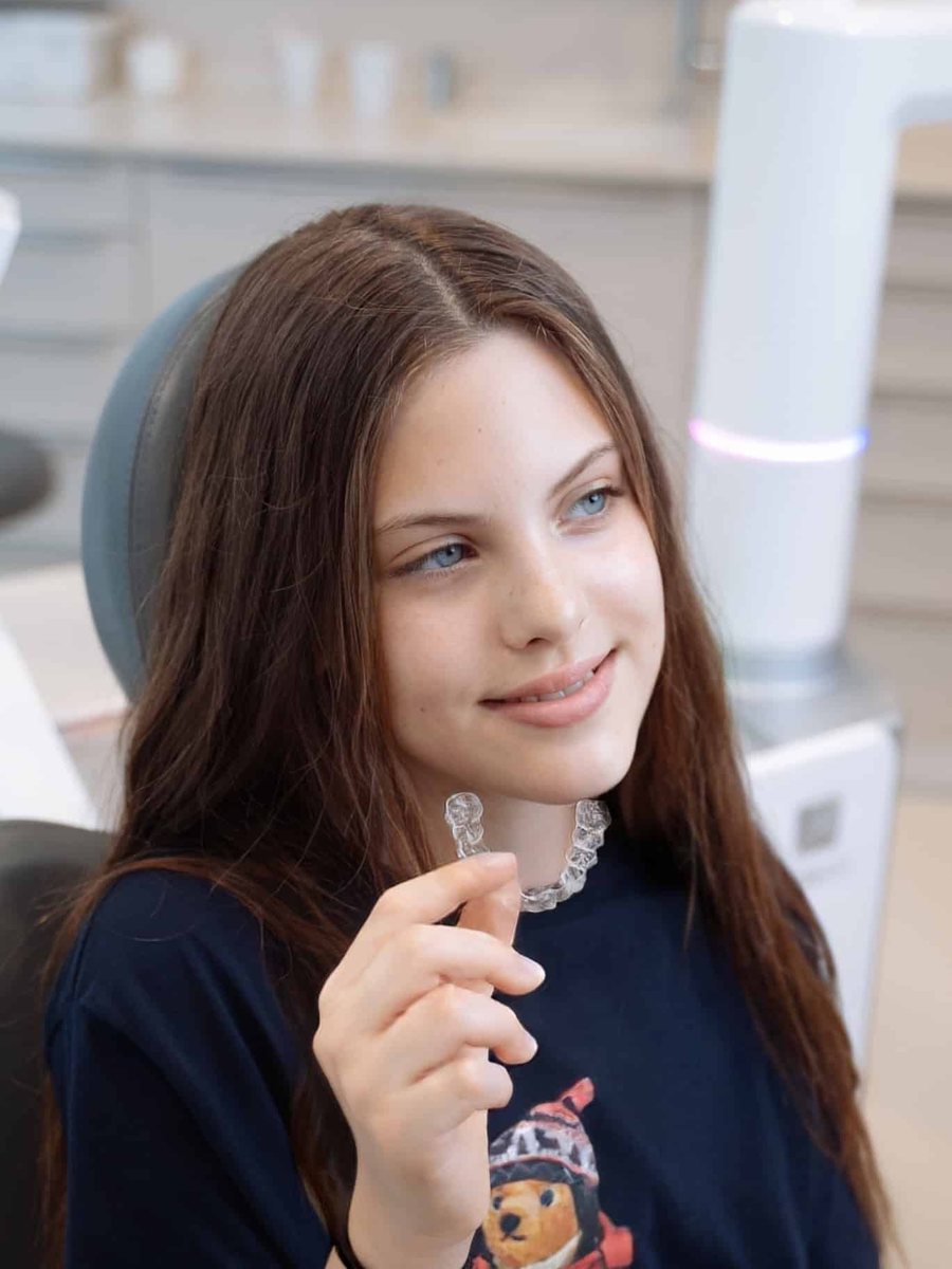Tinejdžerica u ordinaciji Le Clinic drži prozirni Invisalign aligner