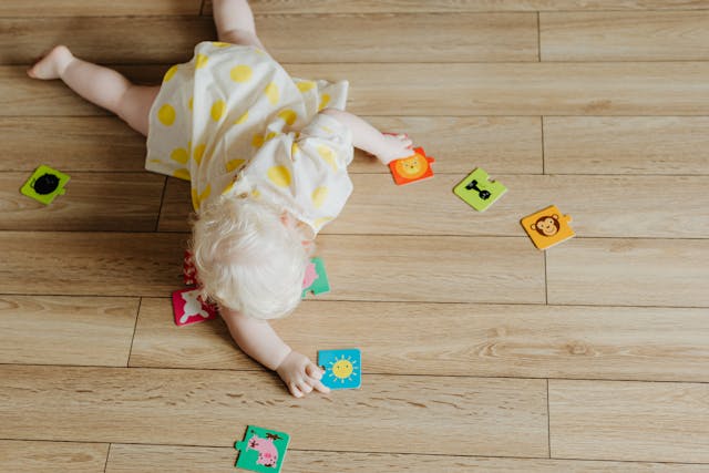 Toddler reaching for puzzle pieces on floor
