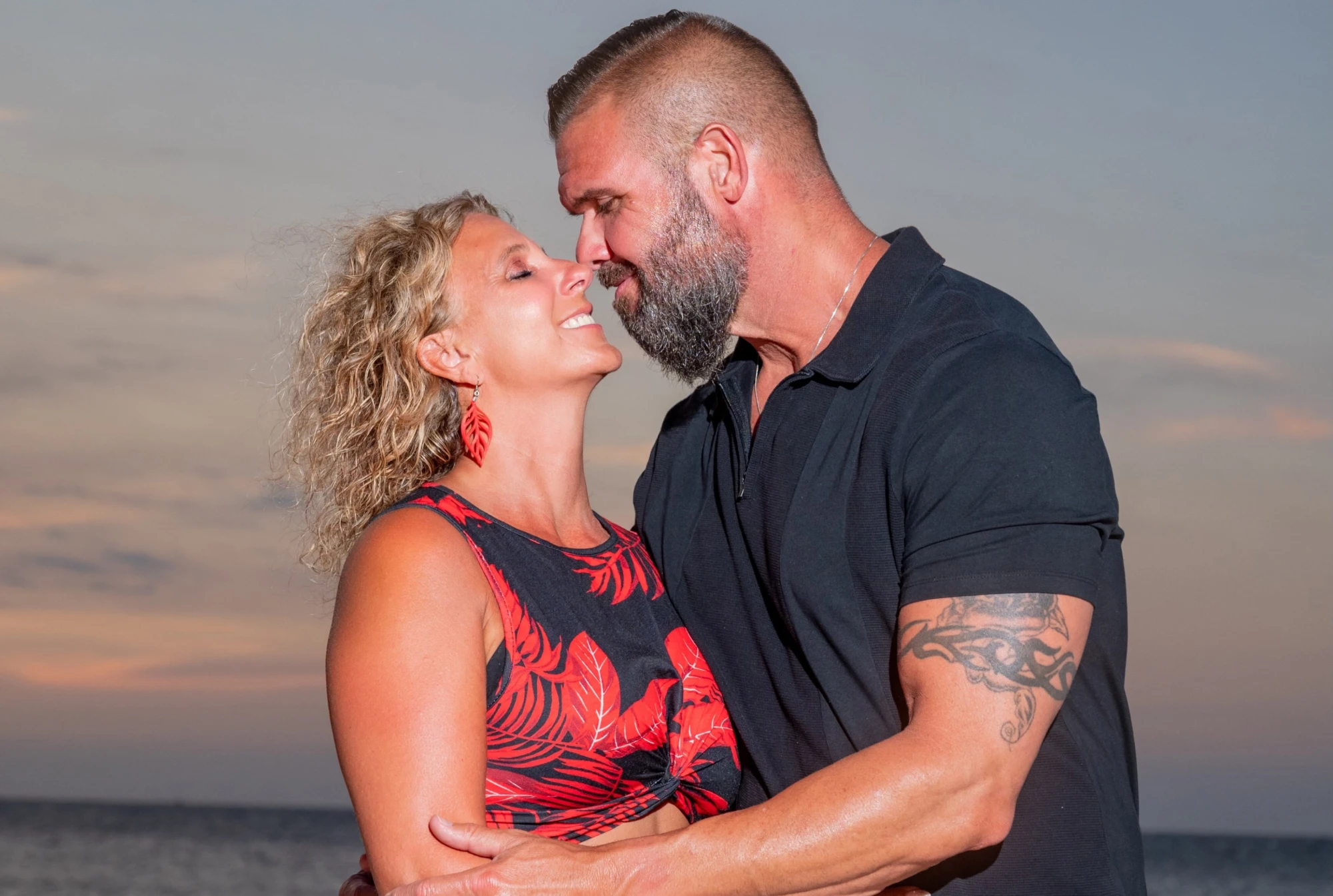 John and Karla Wiser on the beach at sunset, foreheads together