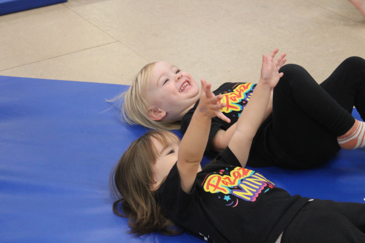 Two young girls smiling and actively engaged in the Minis class.