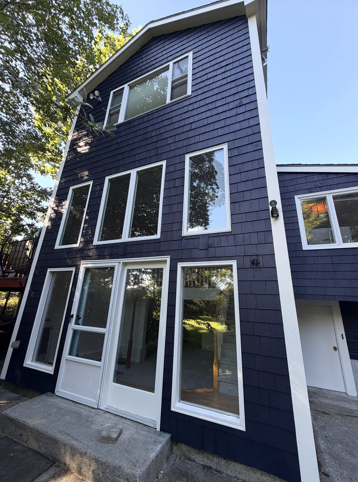 The same three-storey elevation repainted deep navy with crisp white window trim.