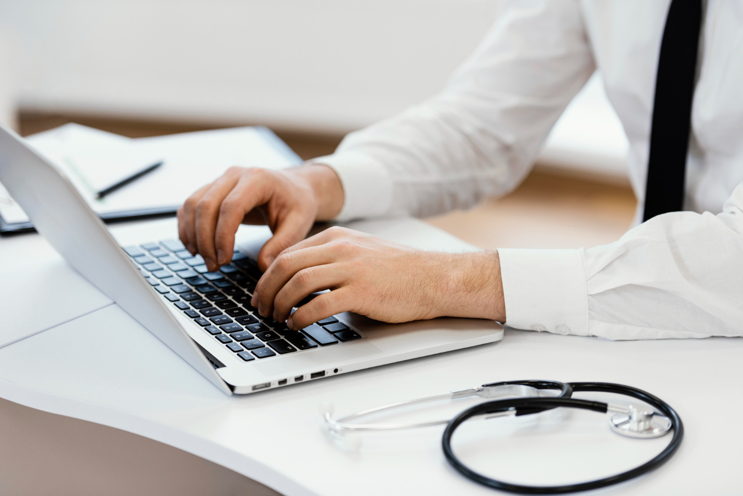 Close-up doctor hands typing on keyboard