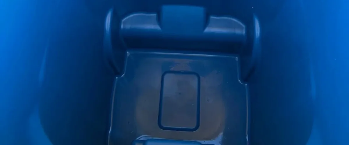 A close-up, high-angle view looking down into the dark blue interior of a plastic bin or container. A close-up, high-angle view looking down into the dark blue interior of a plastic bin or container.
