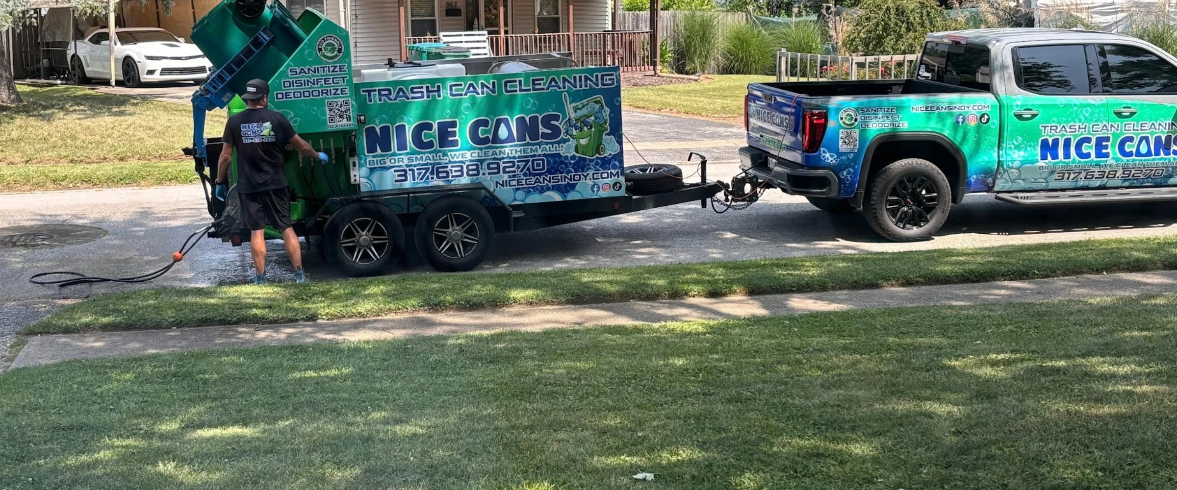 A person operating a trash can cleaning machine on a trailer, hitched to a branded pickup truck, on a sunny street. A person operating a trash can cleaning machine on a trailer, hitched to a branded pickup truck, on a sunny street.