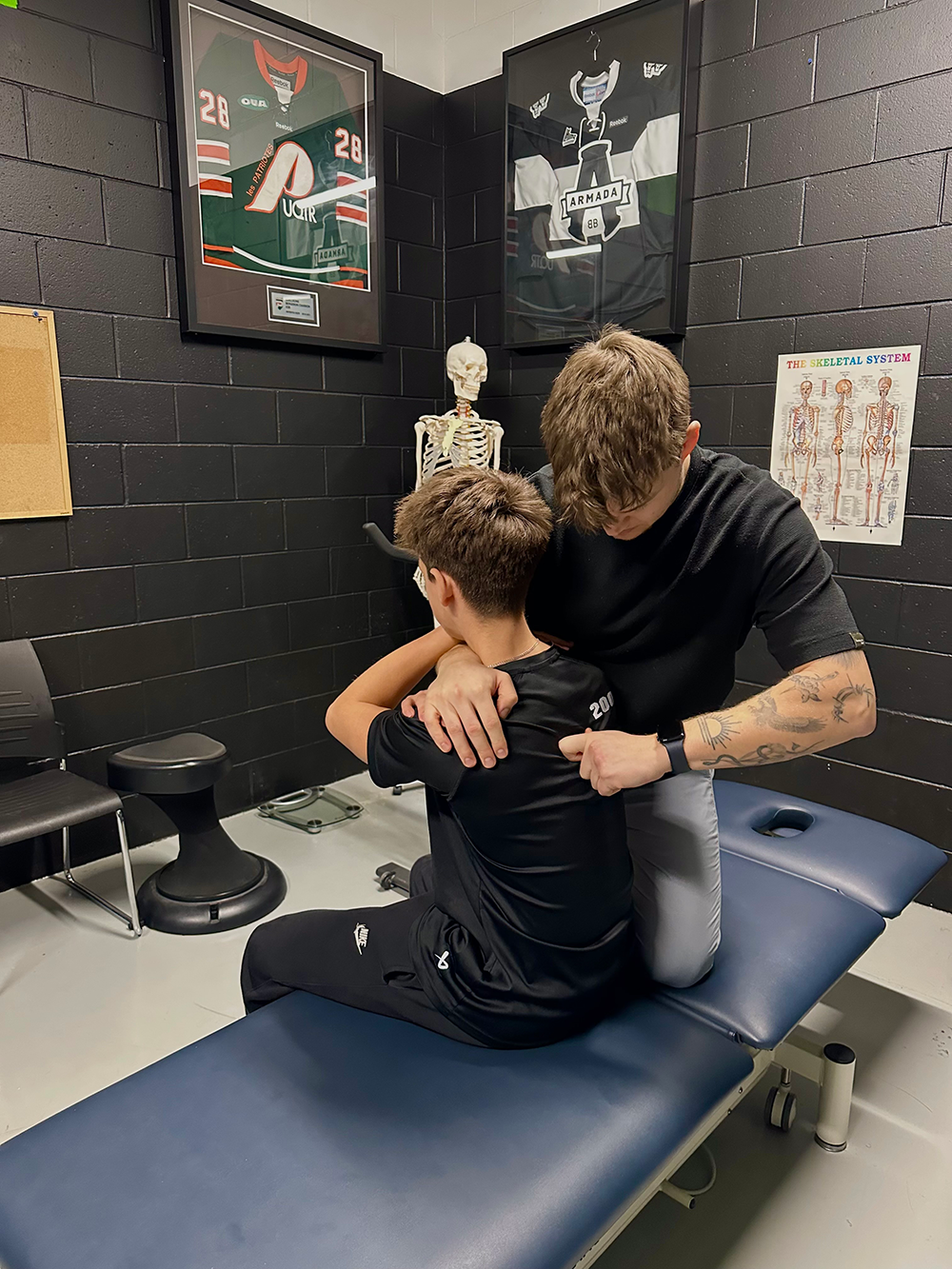 Un physiothérapeute (physio) effectuant un traitement manuel de l'épaule dans une clinique de physiothérapie.