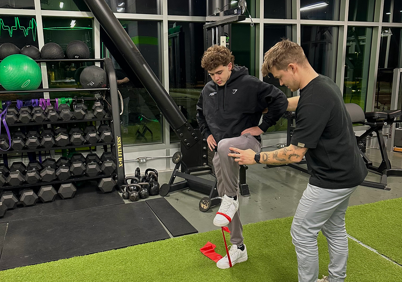 Un physiothérapeute (physio) guidant un patient dans un exercice d'étirement dans une clinique de physiothérapie moderne et lumineuse.