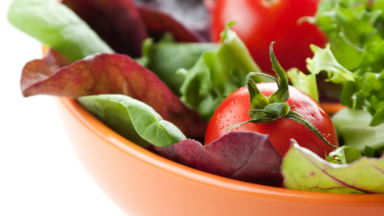 Ripe tomatoes growing alongside salad greens