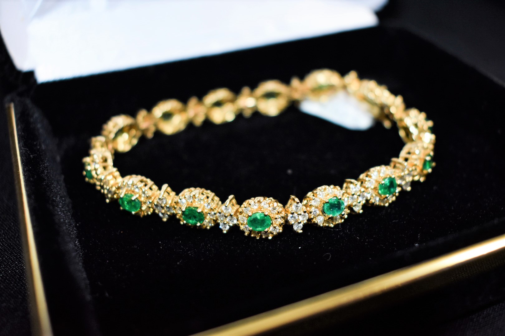 Emerald necklace displayed on a grey bust