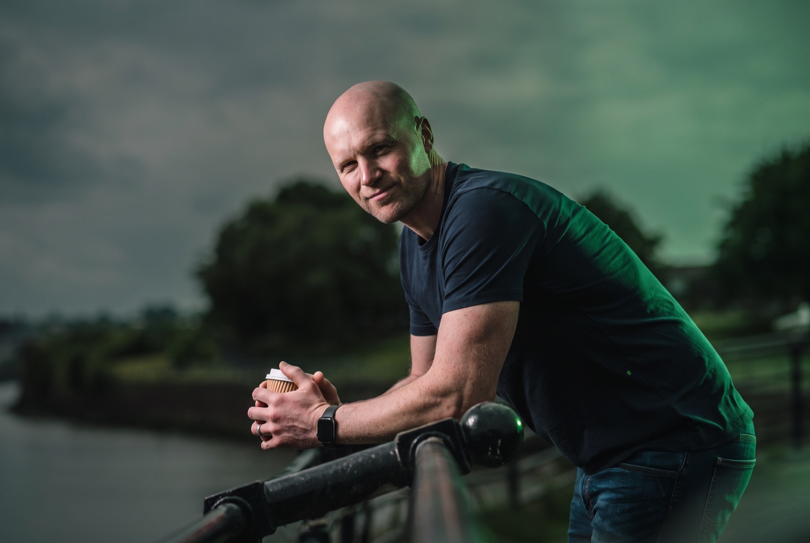 Graham Hurst leaning on a railing by the canal with a coffee
