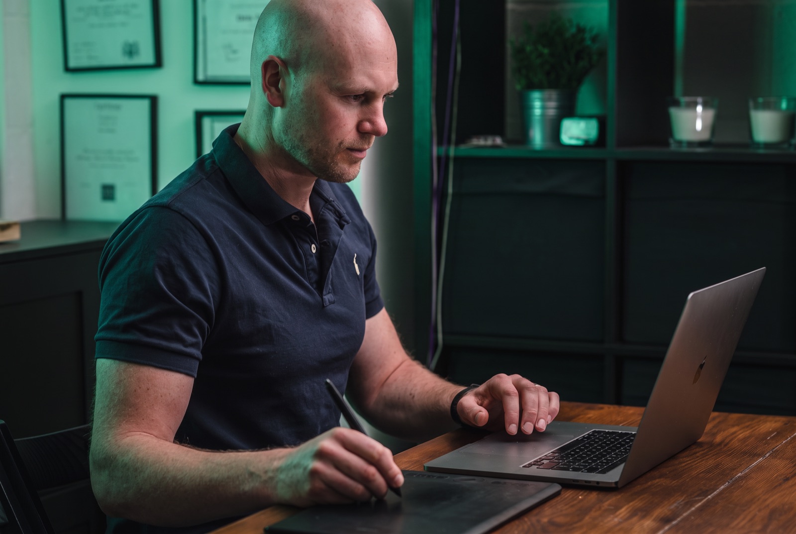 Graham Hurst at his desk, building a client's system on a laptop and drawing tablet