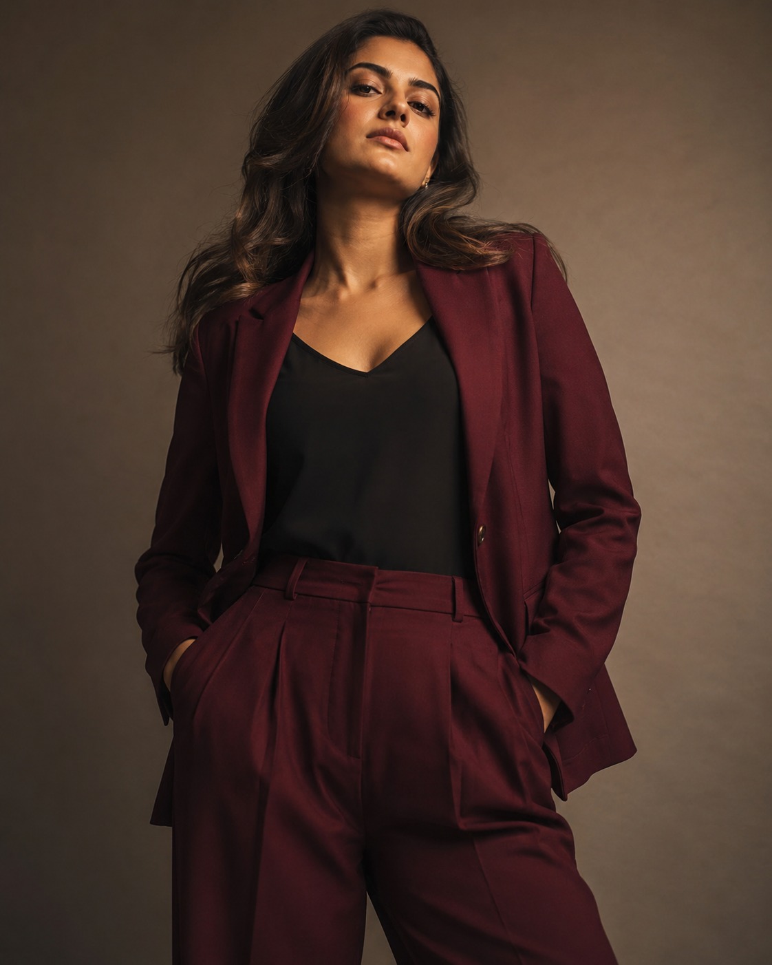Woman in a tailored deep wine-red suit standing confidently in a studio