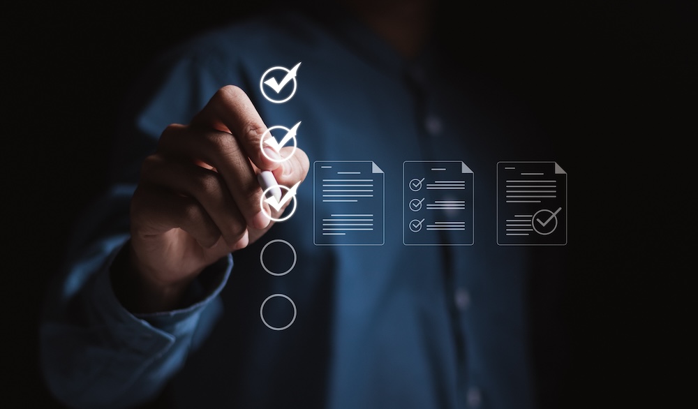 Hand checking off tasks on a digital checklist, representing project management and task delegation for effective business operations.