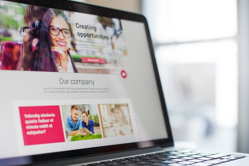 Laptop displaying a digital media company website, featuring a smiling woman and sections titled "Creating opportunities" and "Our company," emphasizing digital services for audience engagement.
