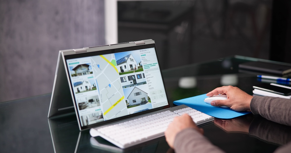 Person using a laptop displaying real estate property listings and maps, emphasizing real estate support services for efficient task management.