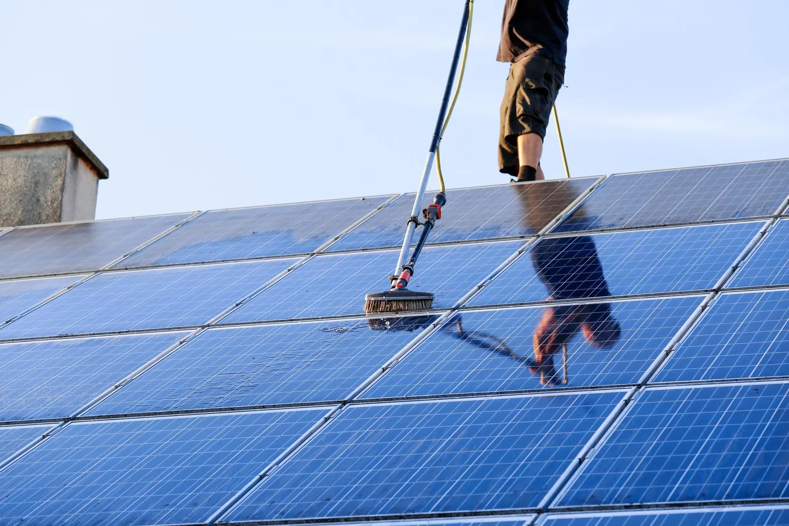 Gloved hands cleaning a solar panel with a cloth