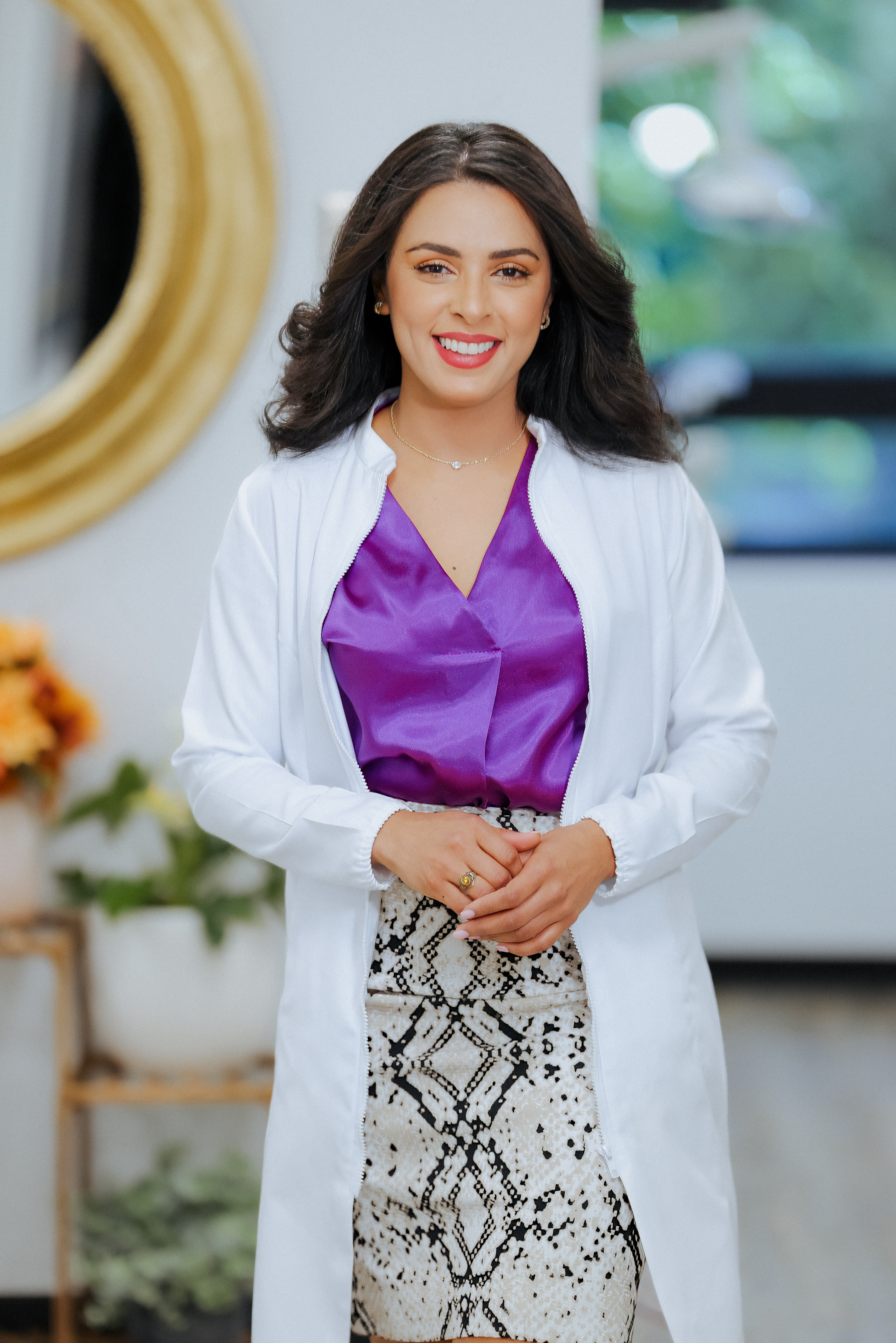 Portrait of a female dental professional wearing a white coat and purple scrubs in a modern dental office