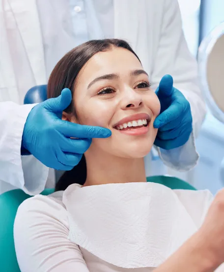 Patient smiling during dental checkup while dentist wearing gloves gently examines teeth in modern clinic setting