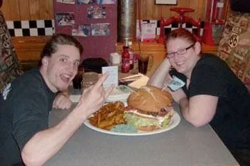 Guests posing with a giant burger challenge plate