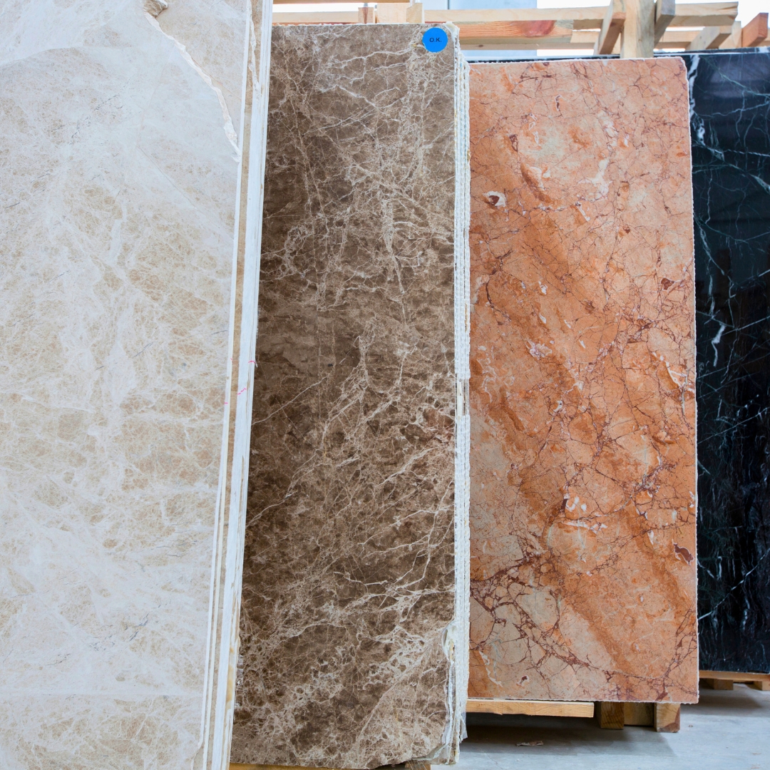 Hands holding quartz countertop samples in beige and light gray from ELCI Cabinets and Floors, with a variety of countertop color options displayed in the background. High-quality quartz selections for cabinets and flooring projects.