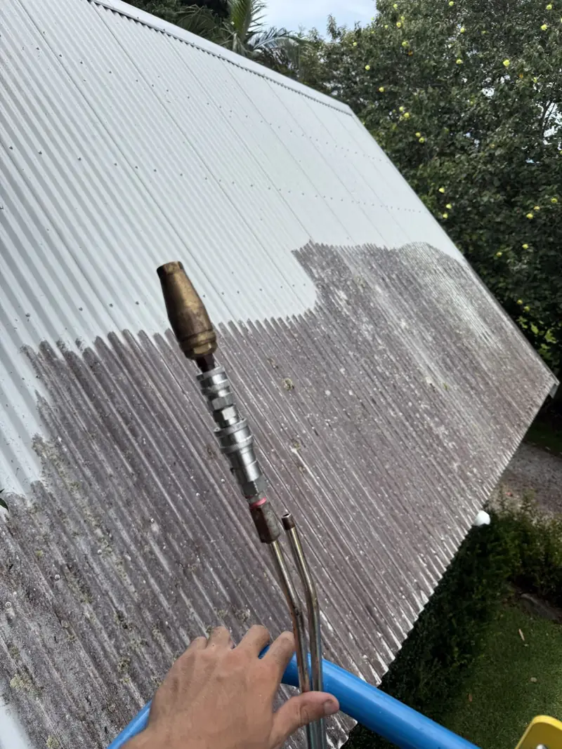 Corrugated metal roof part-way through cleaning, with the cleaned section beside the dirty section