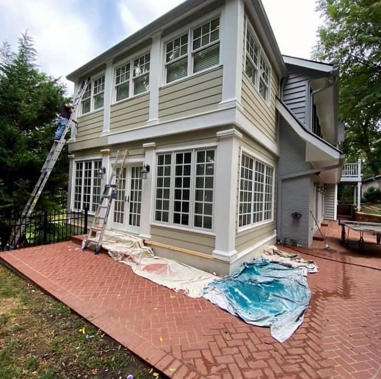 Weatherboard house mid-repaint with drop sheets and ladders