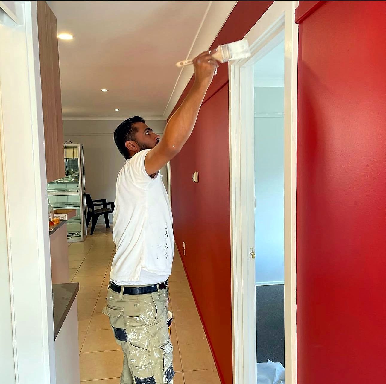 Painter cutting in a crisp edge on a red feature wall