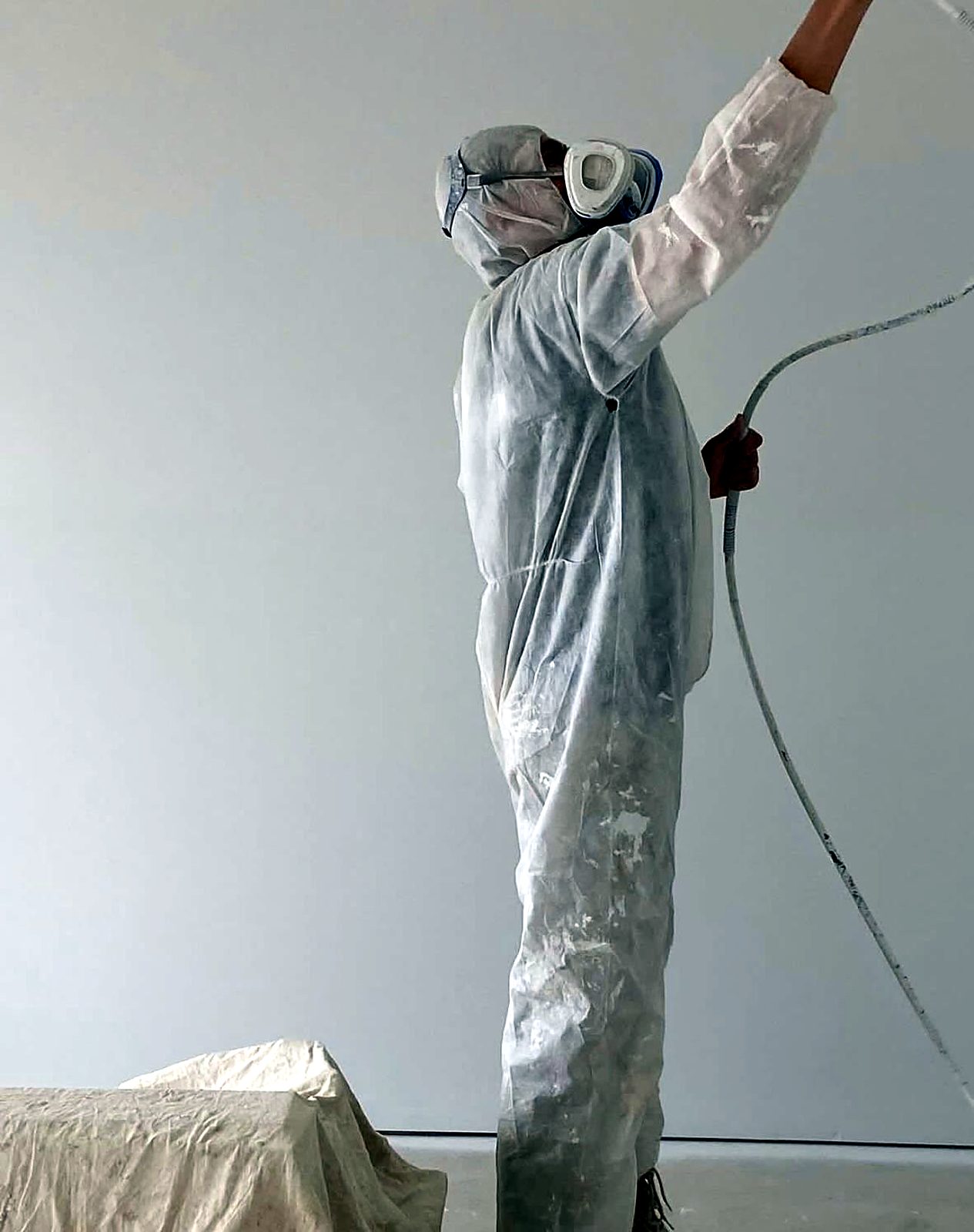 Painter spraying a ceiling in protective gear