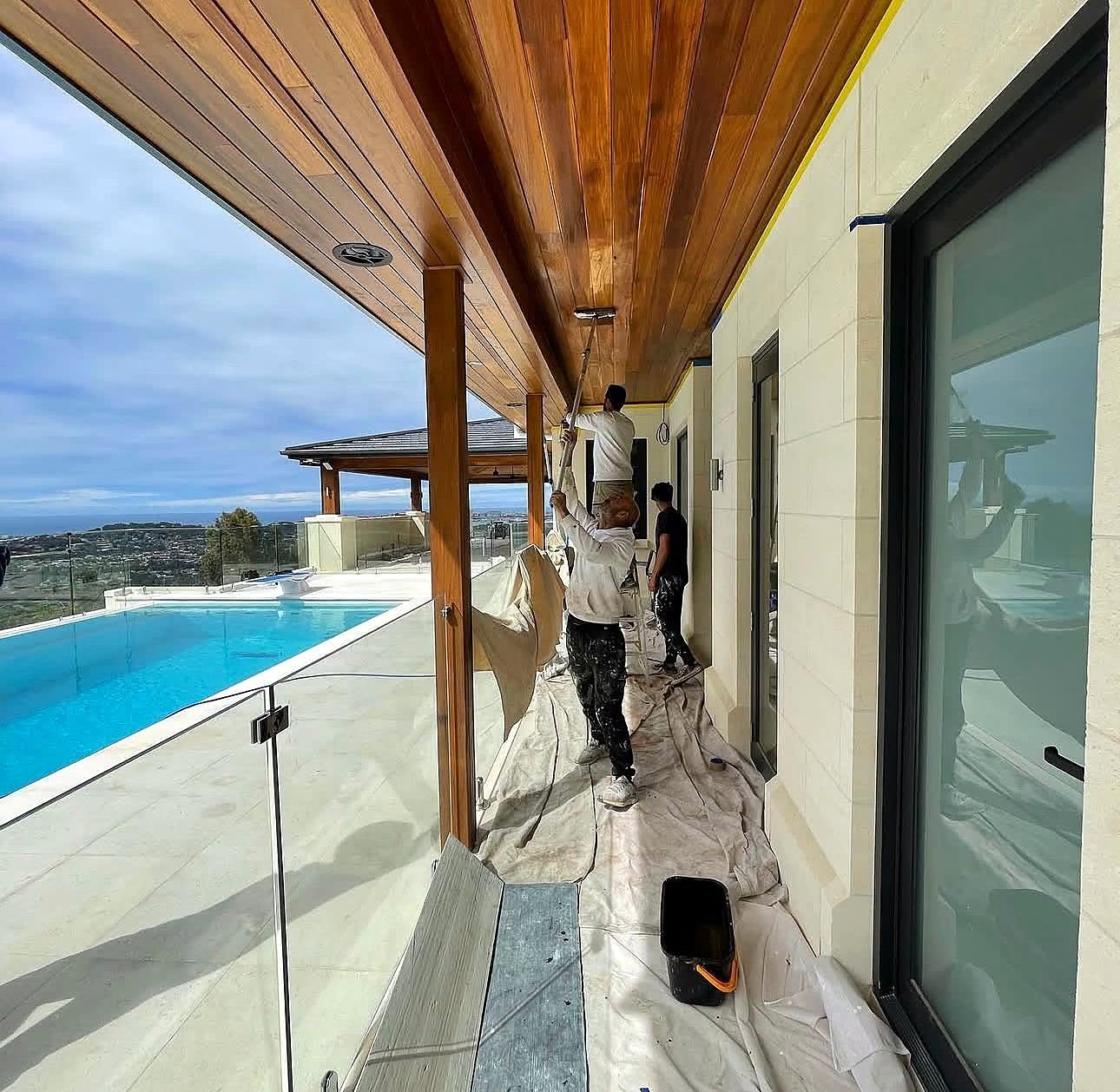 Painters working on a covered verandah beside a pool