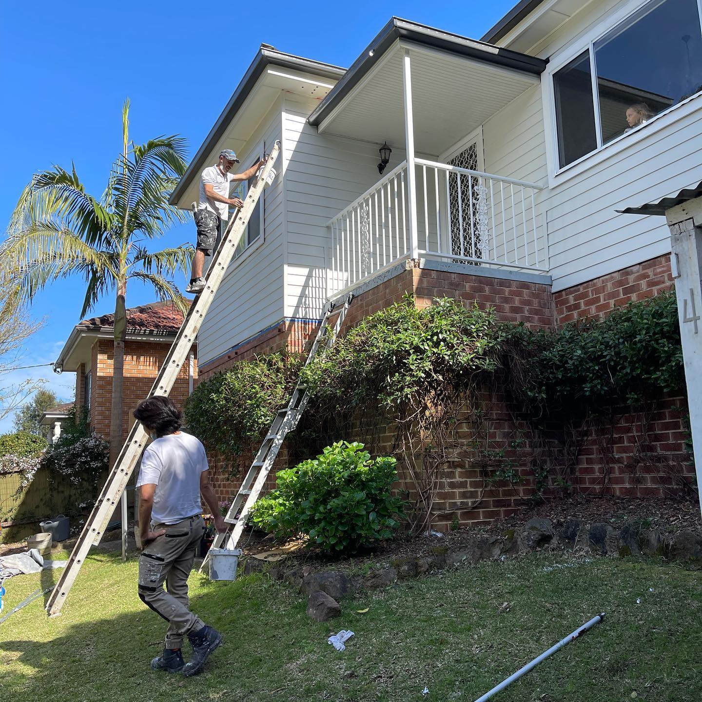 Painters on ladders repainting a two-storey home