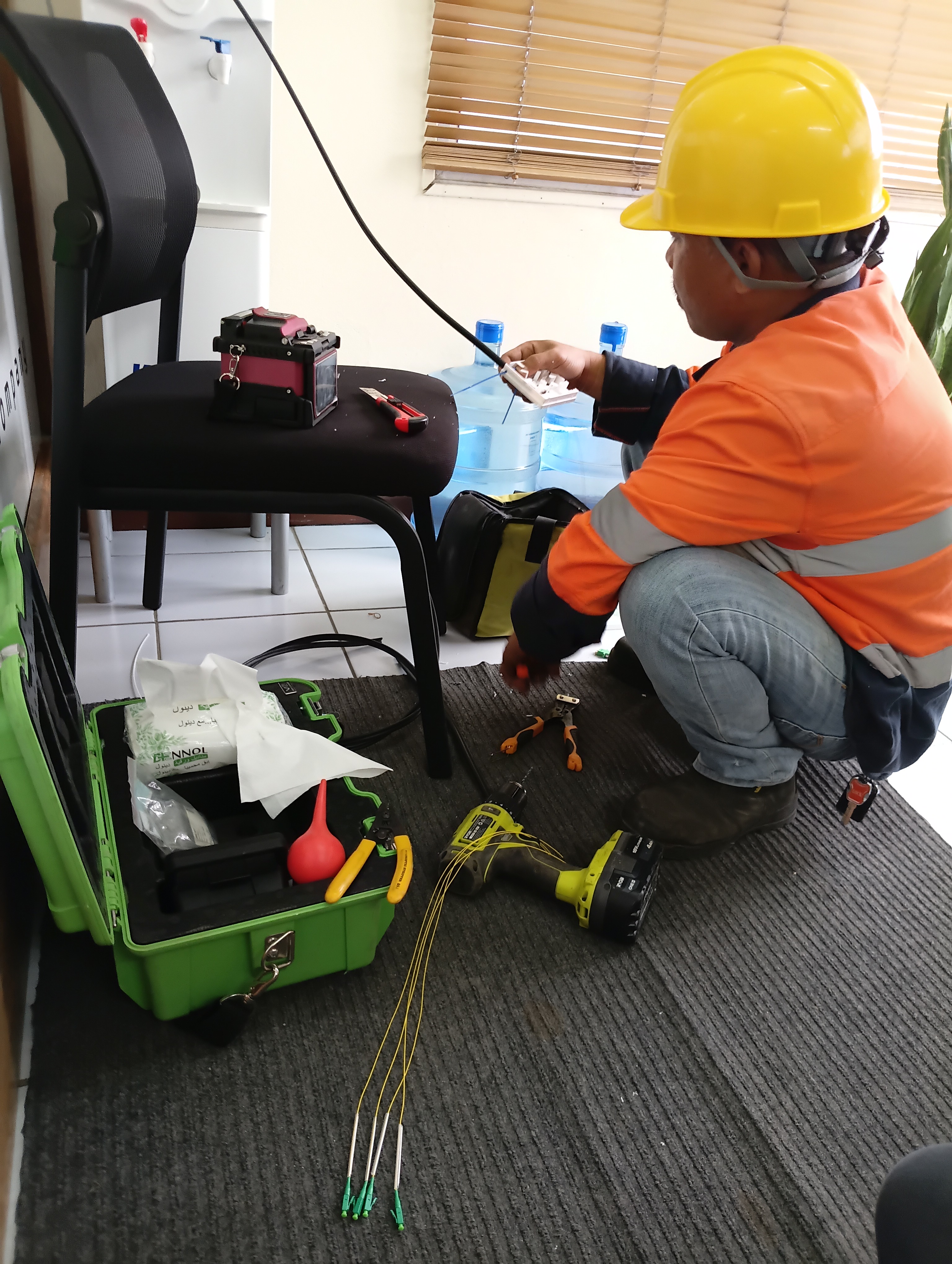 ODC technician terminating fibre pigtails on an office floor in Vanuatu with a fusion splicer set up beside him