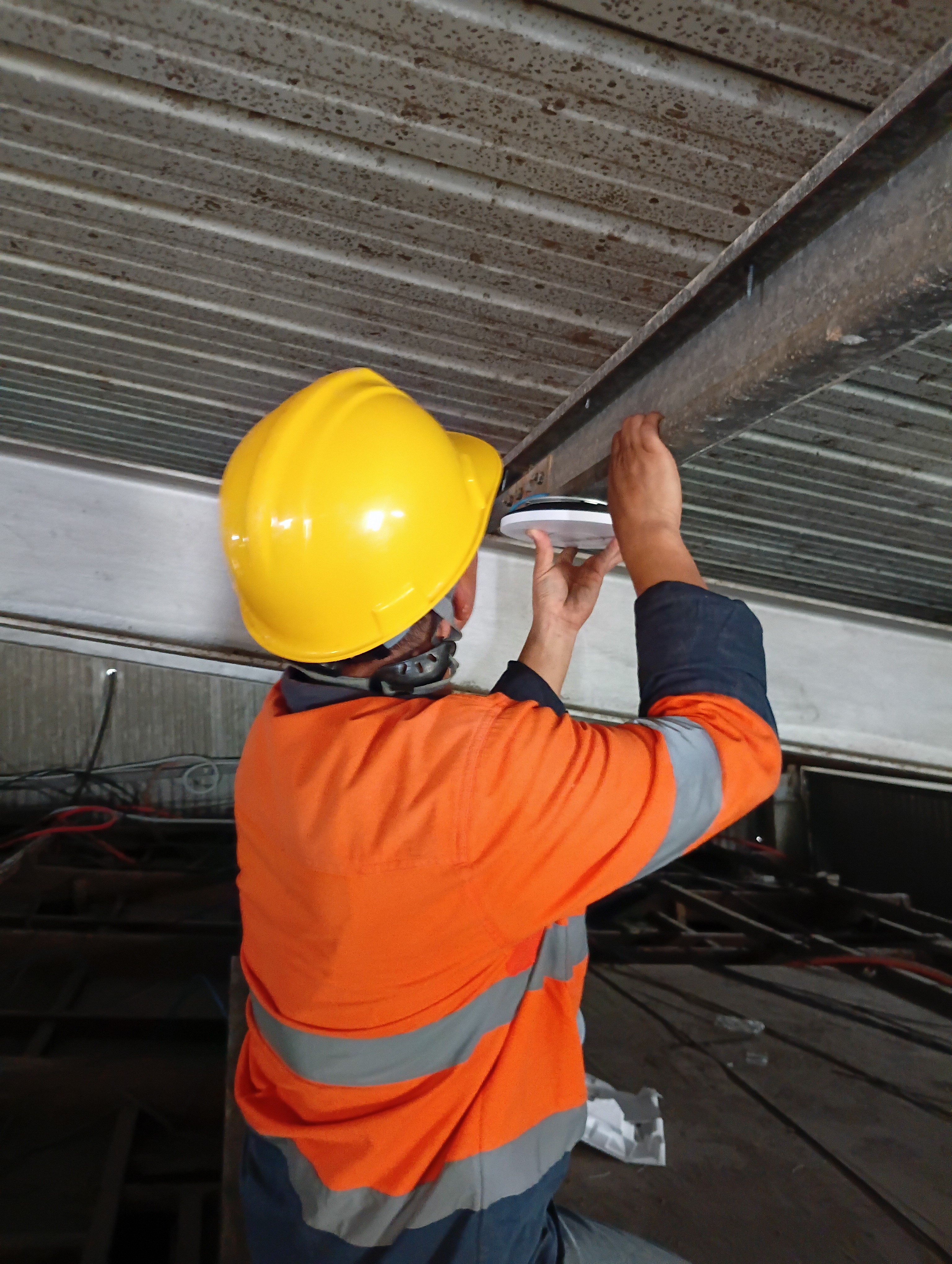 ODC technician mounting a Ubiquiti UniFi wireless access point to a ceiling beam on a commercial site in Vanuatu