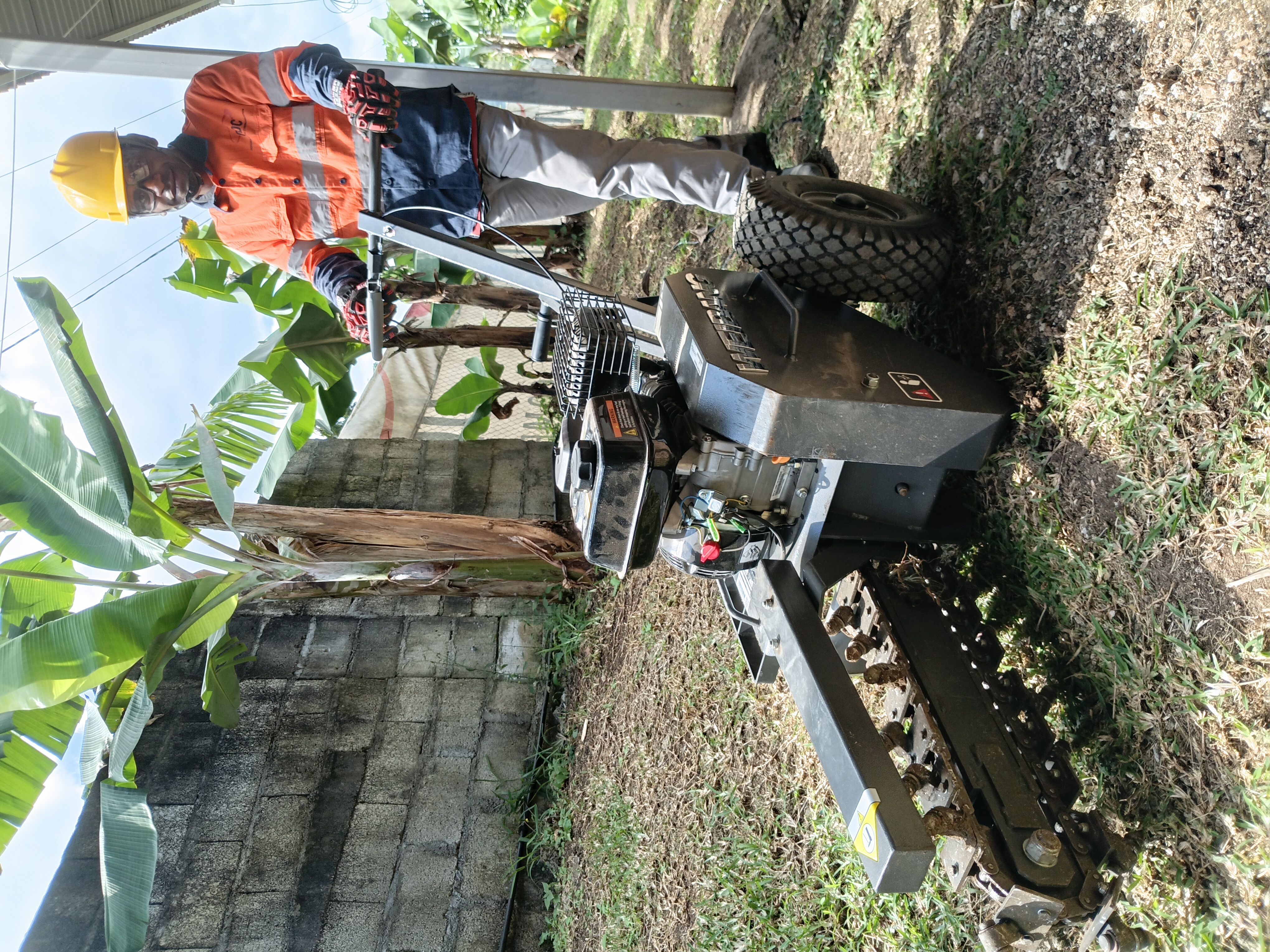 ODC technician operating a walk-behind trencher to lay underground fibre conduit past banana trees in Port Vila, Vanuatu
