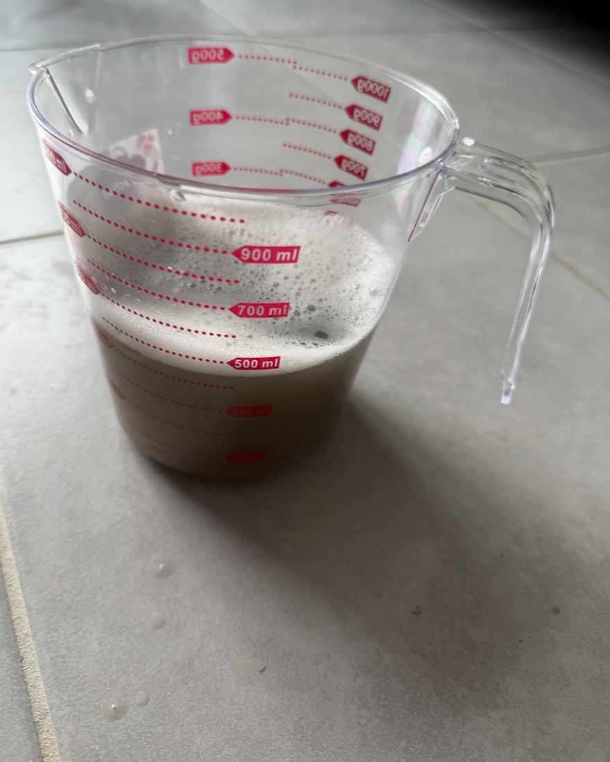 Nettoyage canapé Toulouse : eau extraite d’un canapé dans un verre doseur