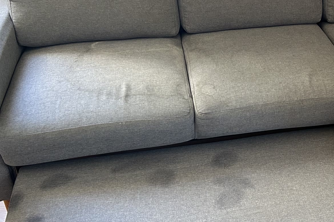 Pipi sur le canapé : auréole d’urine sur les assises d’un canapé gris, avant nettoyage