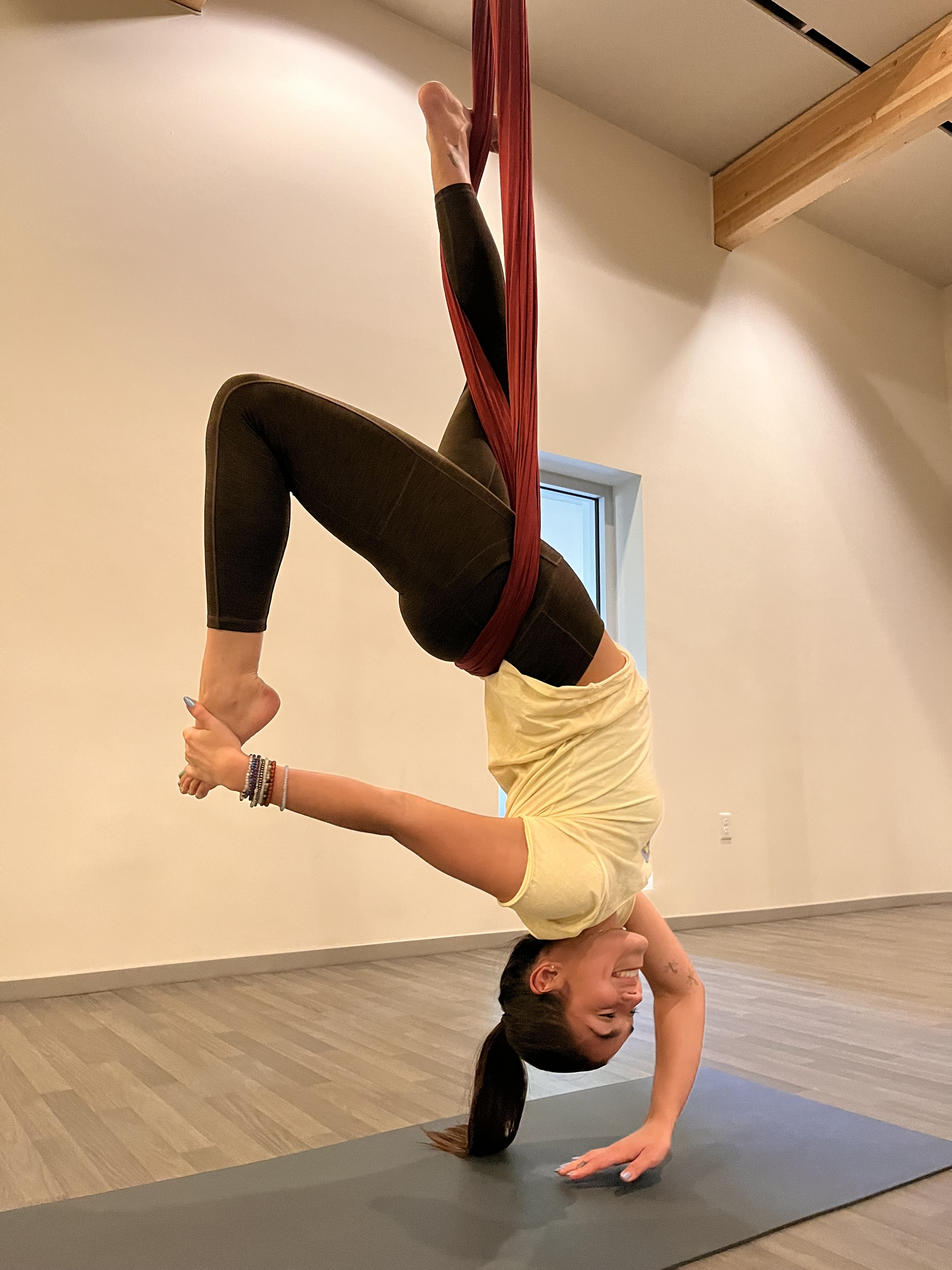 Zoe practicing aerial yoga in a bright studio