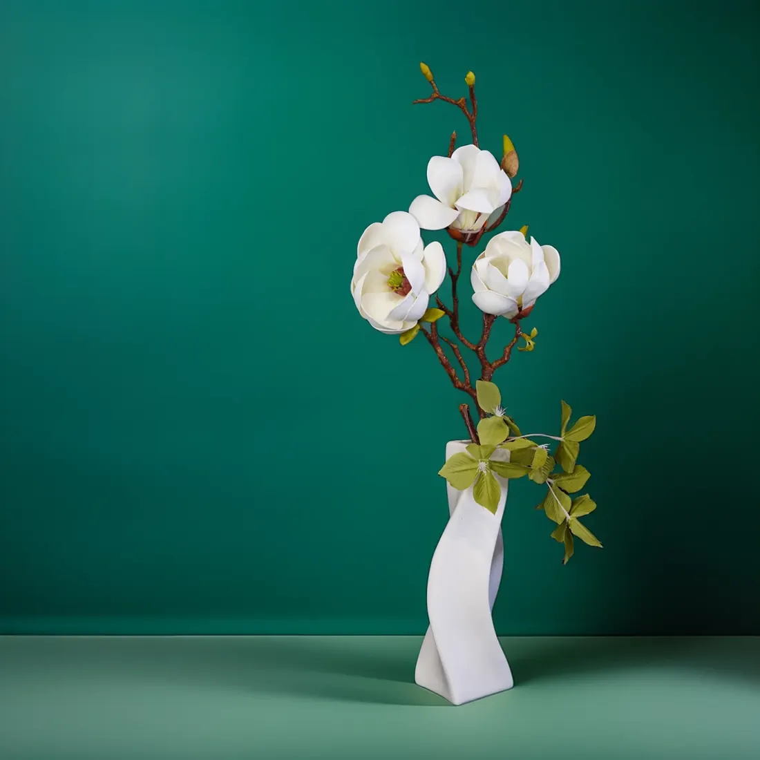 Ikebana-style arrangement with a magnolia branch in a white porcelain vase with a twisted shape