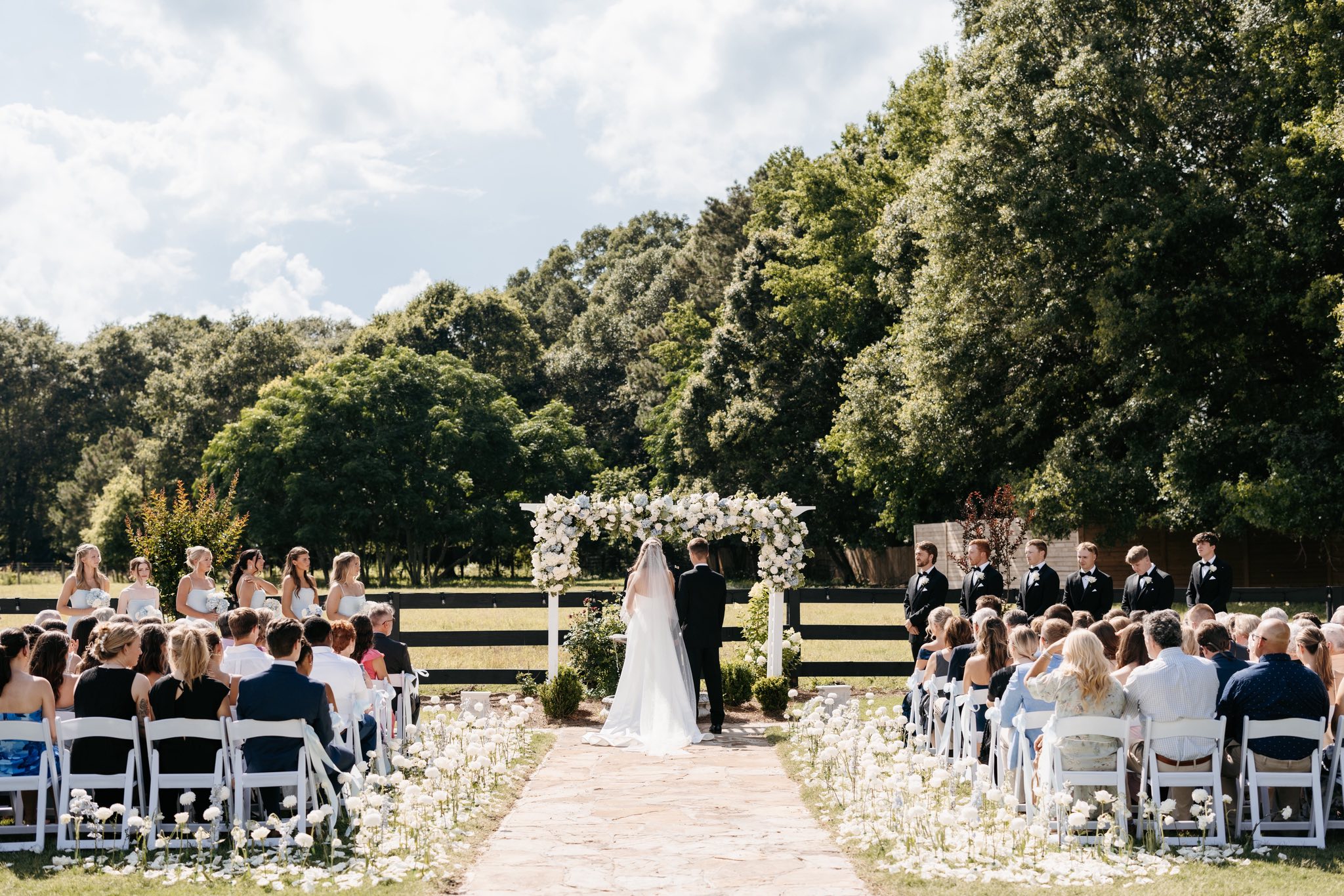 Outdoor wedding ceremony at The Grove Estate with a white floral arch and flower-lined aisle in Crawford, GA
