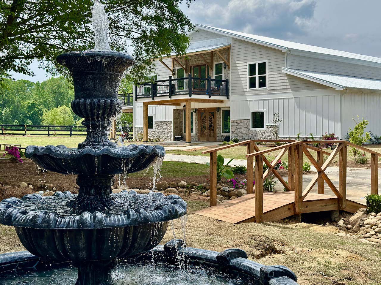 Exterior of The Grove Estate wedding venue with a tiered fountain and footbridge in Crawford, GA