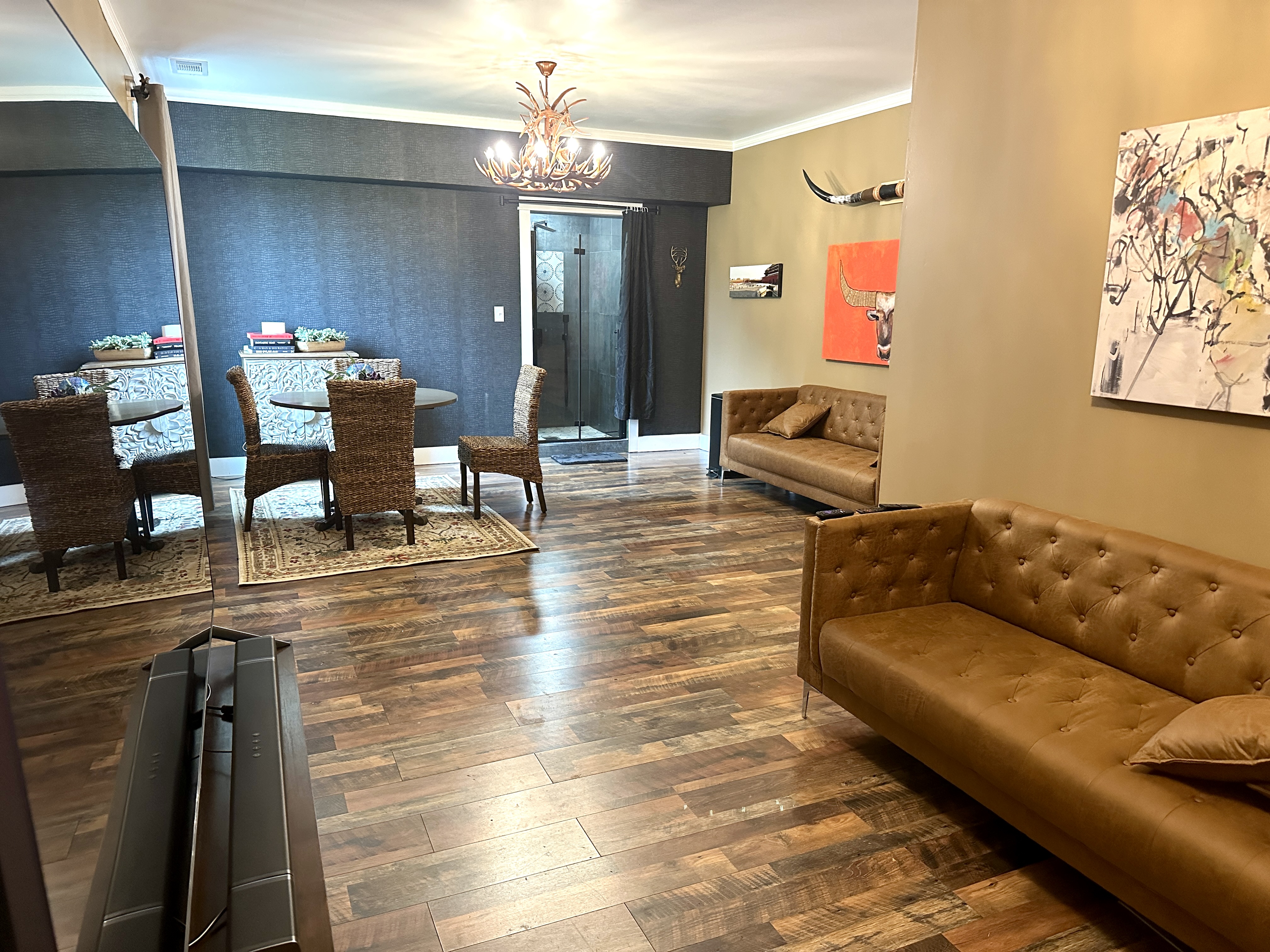 The Grove Estate's groom's suite lounge with tan leather sofas, an antler chandelier, and longhorn wall art