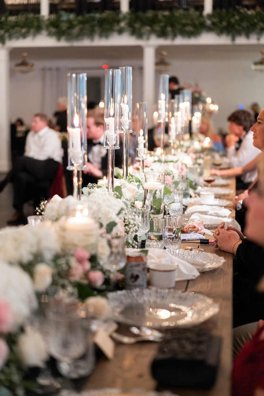 Long candlelit reception table at The Grove Estate with tall taper candles, blush and white florals, and seated guests
