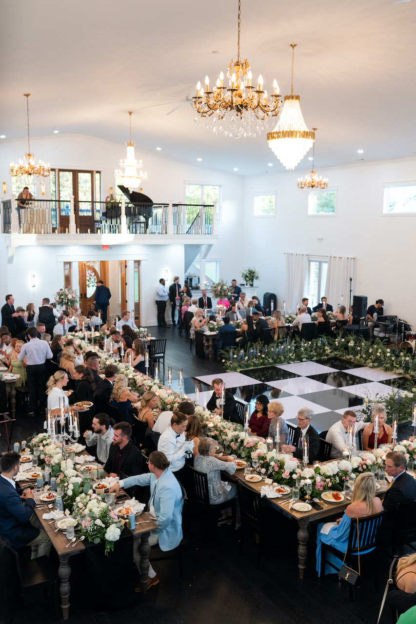 Wedding reception in The Grove Estate's Grand Hall: floral-topped tables, a checkered dance floor, and crystal chandeliers Wedding reception in The Grove Estate's Grand Hall: floral-topped tables, a checkered dance floor, and crystal chandeliers