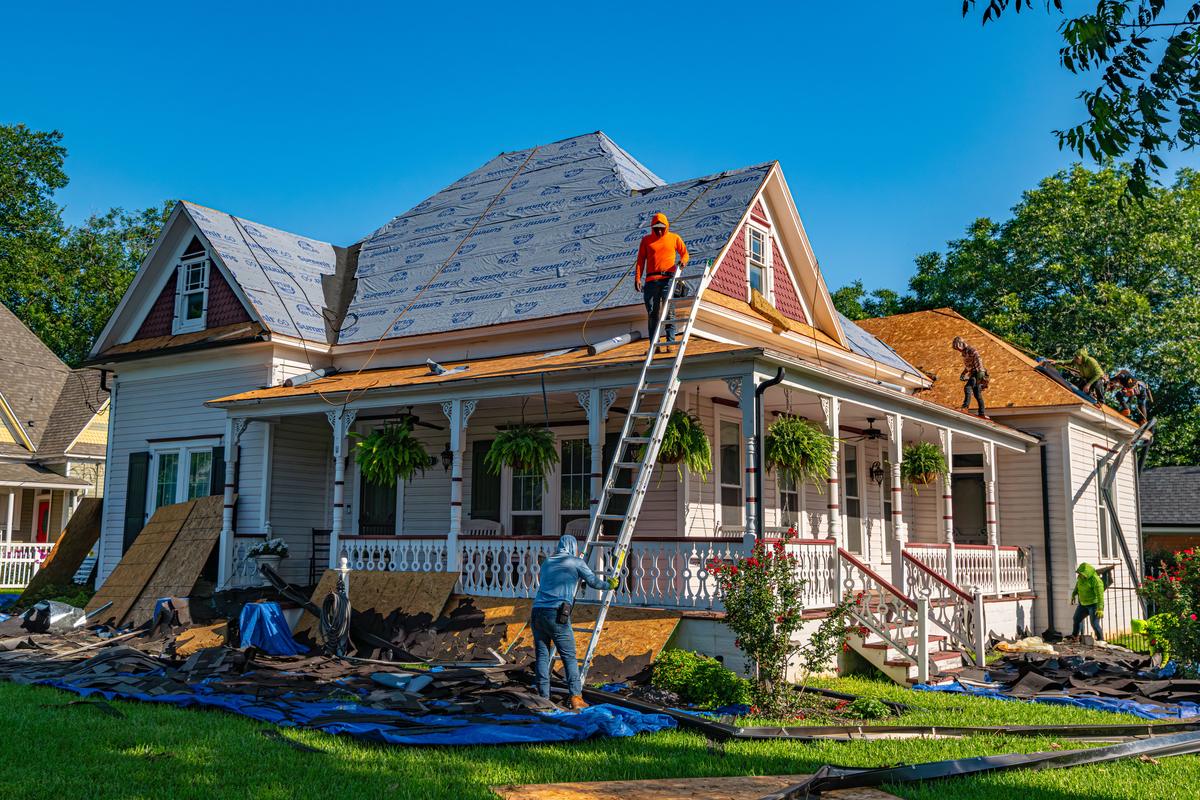 Crew installing synthetic underlayment during a full roof replacement